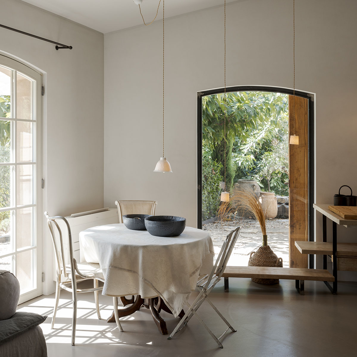 Front view of the kitchen area with a table and chairs on the left, furniture on the right. The interior is modern and minimalist.